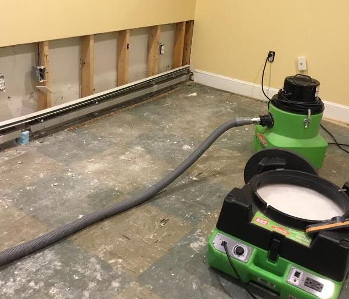 Carpeting and drywall up to 2 feet have been removed from the same bedroom.  An extractor and air scrubber are also visible