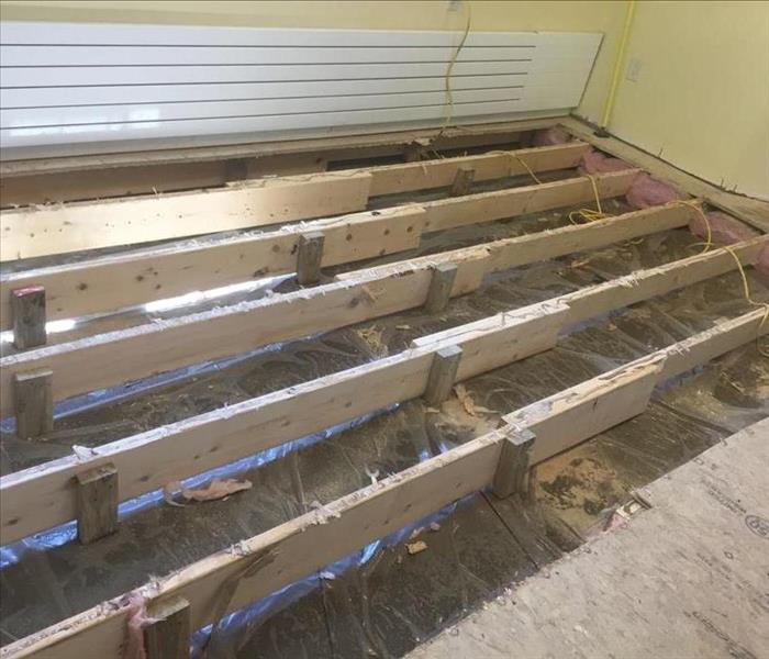 sheathing removed revealing the floor joists and vapor barrier