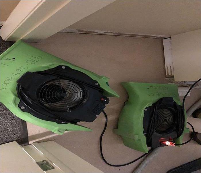 A closet in an office with carpeting removed and air movers placed to force air onto wet walls