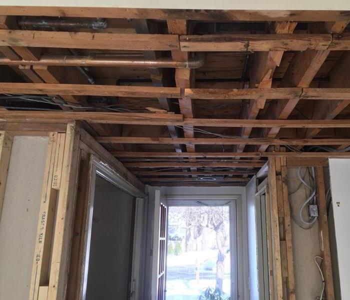 Drywall removed from the ceiling to expose wood structure that has been dried and is ready for new wall board to be installed