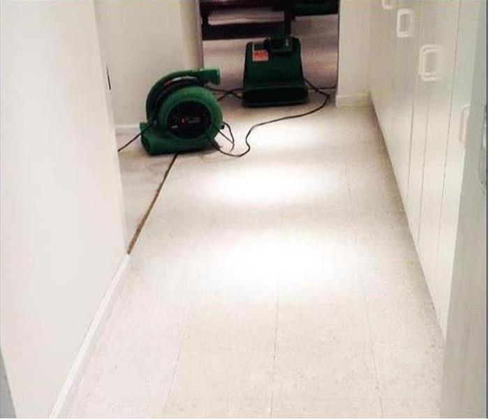 A hallway with carpet removed from the flor and drying equipment installed.