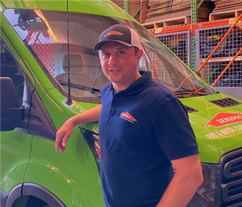 A man standing in front of a green vehicle. 